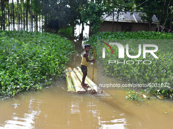A boy row a makeshift raft past submerged houses at a flood-affected village at Juripar village near Kampur  in Nagaon  in the northeastern...