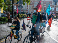 Climate activists and students are seen crossing the Rijksmuseum with their bikes at the Museumplein during the Global Climate Strike, in Am...