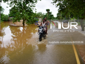 A man ride a bike  through a flooded road after heavy rains at Kachua village  in Nagaon district, in the northeastern state of Assam, India...