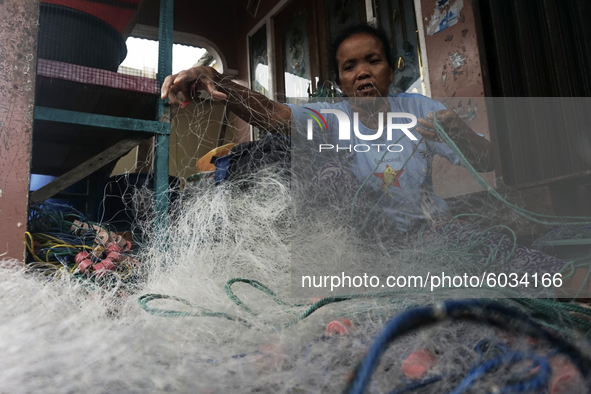 A woman is repairing her husband's fishing nets, who works as a fisherman in Sungsang, Banyuasin Regency, South Sumatra on Saturday, Septemb...