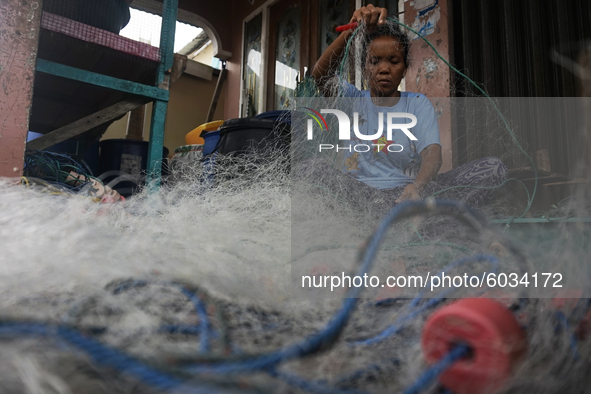 A woman is repairing her husband's fishing nets, who works as a fisherman in Sungsang, Banyuasin Regency, South Sumatra on Saturday, Septemb...