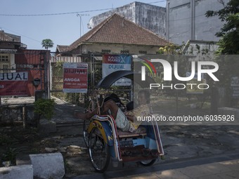 A pedicab driver fell asleep while waiting for passengers in front of the fence of several houses that were sold through property sales serv...