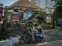 A pedicab driver fell asleep while waiting for passengers in front of the fence of several houses that were sold through property sales serv...