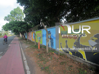 Commuters are seen on the road as they walks past near to the awareness wall painting about COVID-19 coronavirus done by state government fo...