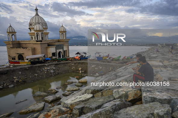 Residents enjoy the view near the floating mosque which collapsed into the sea after being hit by the tsunami on the beach of Kampung Lere,...
