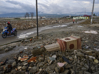 A motorbike rider passes in front of the ruins of a house that was destroyed by the tsunami and has not been torn down in Palu, Central Sula...