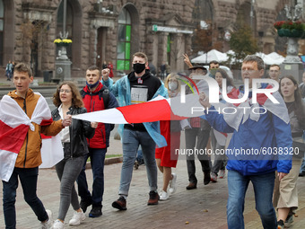 People carry a large historical white-red-white flag of Belarus during a rally of solidarity with Belarusian protests in the center of Kyiv,...
