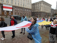 People carry a large historical white-red-white flag of Belarus during a rally of solidarity with Belarusian protests in the center of Kyiv,...