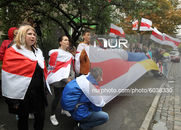 People hold a large historical white-red-white flag of Belarus during a rally of solidarity with Belarusian protests near the Embassy of Bel...