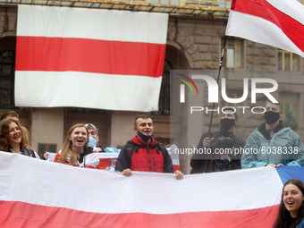 People hold flags in front of the Kyiv City Hall building with a huge former white-red-white flag of Belarus hanging on it, during a rally o...