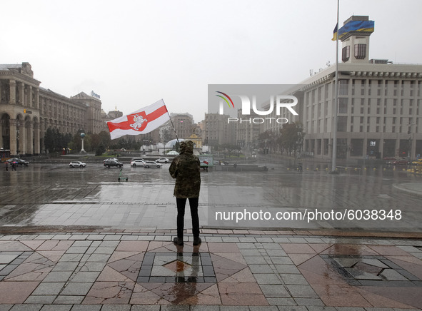 A protestor waves a historical white-red-white flag of Belarus during a rally of solidarity with Belarusian protests while heavy rain on Ind...