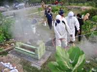 Health Officers from the local City Service, spray disinfectant liquid to prevent the spread of COVID-19, in the mass burial area of ​​victi...