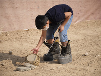An Iranian schoolboy wearing a protective face mask and protective boots holds an anti-vehicle mine as he takes part a symbolic minefield cl...