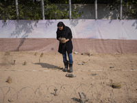 An Iranian woman wearing protective boots holds a Valmara-69 anti-personnel mine as she takes part a symbolic minefield clearing competition...