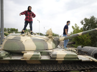 An Iranian man and a woman stand on a military tank while visiting of the holy defense Garden-Museum during a war exhibition to commemorate...