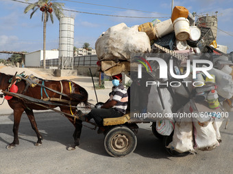 A Palestinian man wearing a protective face mask drives a horse-drawn cart loaded plastic and recyclable materials in Deir al-Balah in the c...