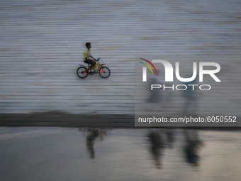 A boy rides a bicycle on the riverside near Dhaka, Bangladesh on October 2, 2020.  (