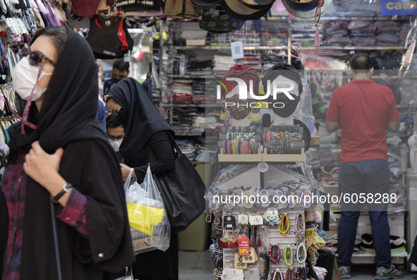 Iranians wearing face masks purchase as two mannequins are covered with face masks in a shop in northern Tehran while the new coronavirus (C...