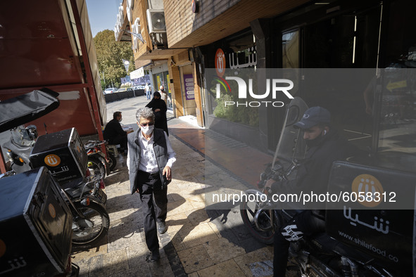 An Iranian man wearing a protective face mask walks along an avenue in northern Tehran while the new coronavirus (COVID-19) disease rapid ri...