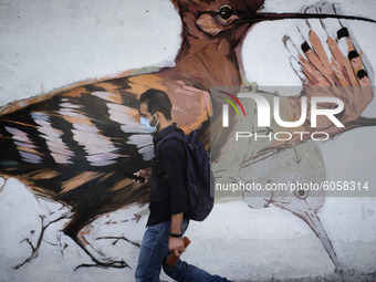 An Iranian man wearing a protective face mask walks past a mural in northern Tehran while the new coronavirus (COVID-19) disease rapid risin...