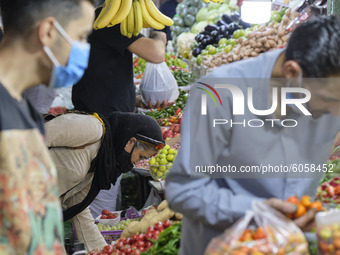 An Iranian woman wearing a protective face mask purchases in a bazaar in northern Tehran while the new coronavirus (COVID-19) disease rapid...
