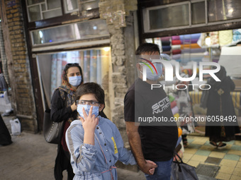 An Iranian family wearing protective face masks walk in a bazaar in northern Tehran while the new coronavirus (COVID-19) disease rapid risin...