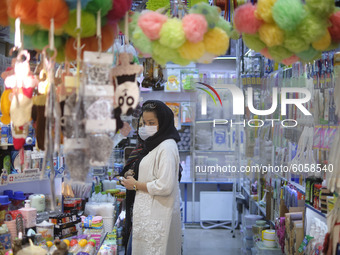 An Iranian woman wearing a protective face mask looks on as she stands in a shop in a bazaar in northern Tehran while the new coronavirus (C...