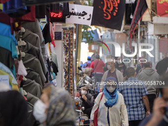 An Iranian woman wearing a protective face mask walks in a bazaar in northern Tehran while the new coronavirus (COVID-19) disease rapid risi...