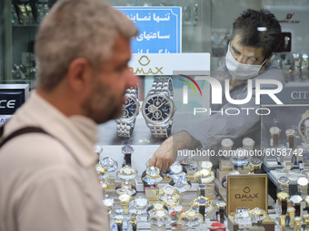 An Iranian trader wearing a protective face mask adjusts his shop window in a bazaar in northern Tehran while the new coronavirus (COVID-19)...