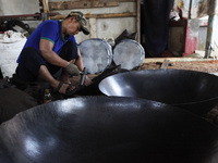 A craftsman works on making a steel wok made of steel plate in the home industry, 