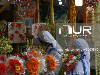 Women buy flowers from a stall in Dhaka, Bangladesh on October 6, 2020. (