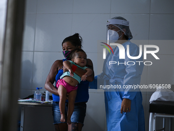 A member of the Brazilian Armed Forces medical team examines a woman and her child  from the indigenous Guajajara ethnic group, amid the Cor...
