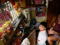 A grade 2 student accompanied by his mother waits for his online class to start at his family's store in front of their home in Manila, Phil...