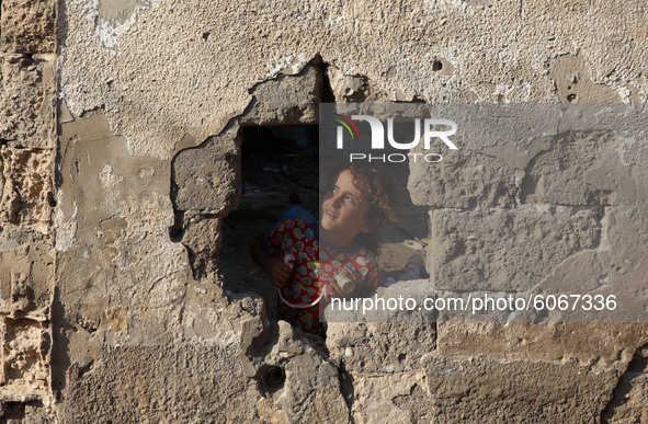 A Palestinian girl looks through a hole in the wall outside her family home in Al-Shati refugee camp in Gaza City on October 8, 2020.
 