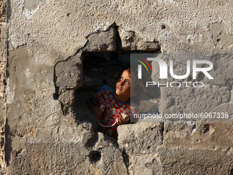 A Palestinian girl looks through a hole in the wall outside her family home in Al-Shati refugee camp in Gaza City on October 8, 2020.
 (