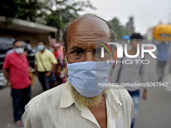 A man wears a face mask amid coronavirus emergency in Kolkata, India,  on 8 October, 2020. People stands on a line without maintaining socia...