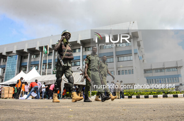 Police officers walk pass officials The Independent National Electoral Commission while distributing the electoral sensitive materials to va...