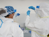 Health workers in Personal Protective Equipment (PPE) suits collect samples from people during the express COVID-19 testing in Alfacar, Gran...
