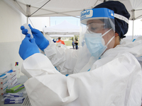 A Health worker in Personal Protective Equipment (PPE) suit collects samples from people during the express COVID-19 testing in Alfacar, Gra...