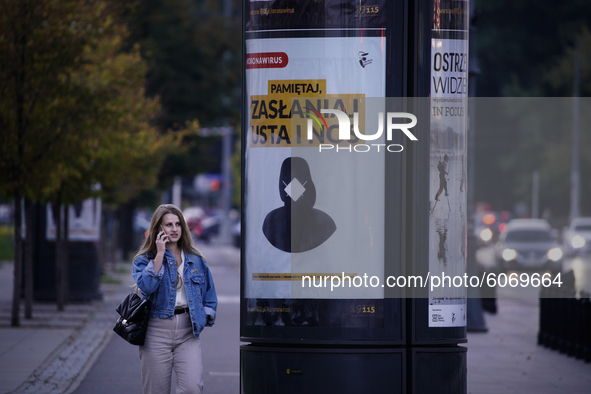 A woman walks past a poster urging the wearing of face masks in Warsaw, Poland on October 8, 2020. The ministry of health on Thursday announ...