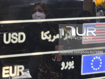 An Iranian woman looks on an electronic board displayed at the currency exchange shop in Tehran’s business district on October 10, 2020. U.S...