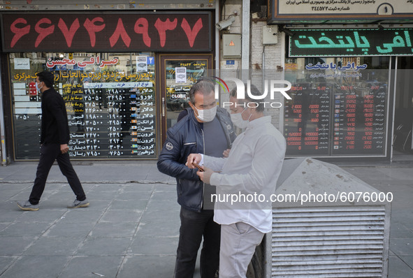 Iranian street money changers use a smartphone to check the price update for the U.S. Dollar as they stand out of currency exchange shop in...