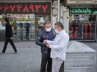 Iranian street money changers use a smartphone to check the price update for the U.S. Dollar as they stand out of currency exchange shop in...