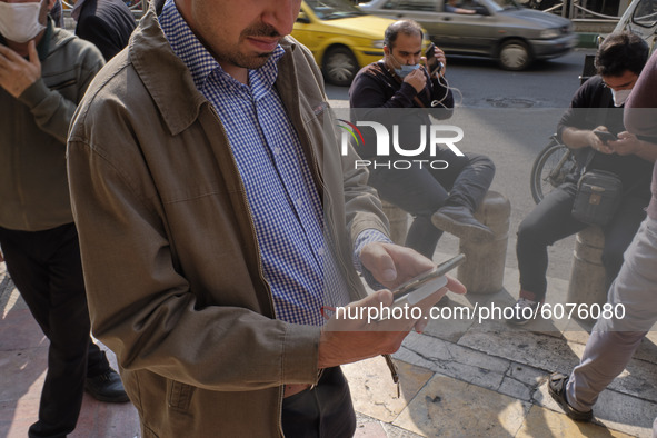 An Iranian street money changer uses a smartphone to check the price update for the U.S. Dollar as he stands on a street-side in Tehran’s bu...