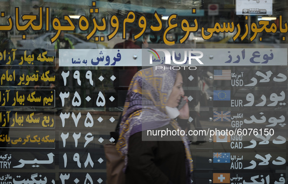 An Iranian woman speaks on her smartphone to check the price update for the U.S. Dollar while standing in front of a currency exchange shop...
