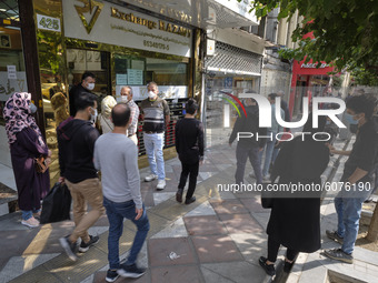 Iranian people stand out of a currency exchange shop as they wait to buy U.S. Dollar in Tehran’s business district on October 10, 2020. U.S....