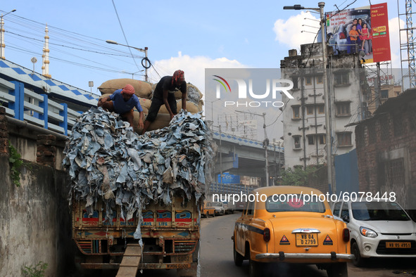 Indian worker carrying tanned animal hides  to lode a truck at a tannery in Kolkata,India on October 11,2020.The air of Kolkata  is polluted...