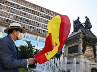 A man with a mask with the slogan Long live the King waves a Spanish flag at the Isabel La Catlica and Christopher Columbus monument during...