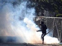 A protester returns a tear gas canister fired by Indian police near the gun-battle site in Barzulla area of Srinagar, Kashmir on October 12,...