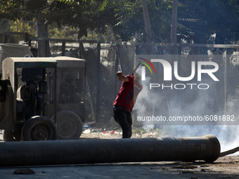 A protester returns a tear gas canister fired by Indian police near the gun-battle site in Barzulla area of Srinagar, Kashmir on October 12,...